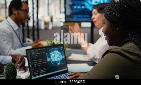 System administrators in startup office brainstorming leverage AI tech to gain competitive edge. . Management executives doing meeting to discuss training machine learning predictive models, camera A Stock Photo