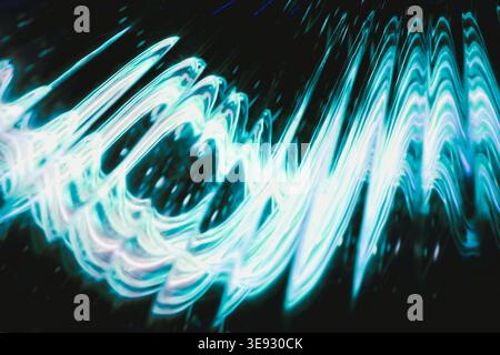 Luminous cyan and white wavy light ripples on black surface Stock Photo