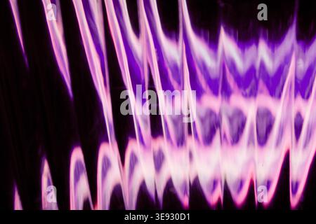 Wavy purple and pink neon light patterns reflected through textured glass Stock Photo