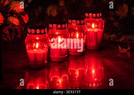 Grave candles burning brightly in a cemetery at night, honoring the memory of loved ones Stock Photo