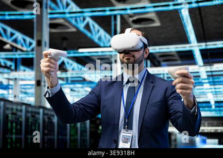 Data center programmer uses VR headset gear to conduct security audits and protect against cyber threats. Man uses virtual reality technology to implement cybersecurity measures in server farm Stock Photo