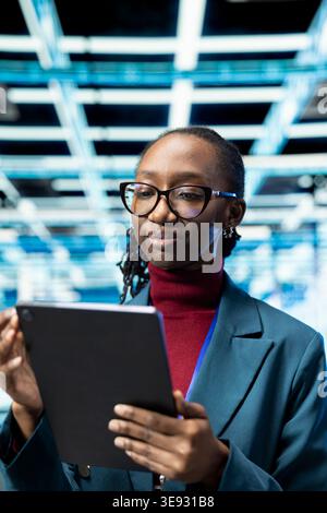 Close up of data center female programmer using tablet to upgrade database storage equipment. Woman in server room uses touchscreen device to update cloud computing rigs systems, technology concept Stock Photo
