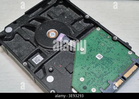 A close-up of a dusty, old hard disk drive highlighting its green circuit board. It perfectly captures obsolete technology and data storage history. Stock Photo