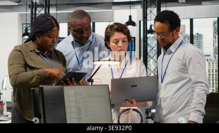 Portrait of smiling engineering team in office automating workflows using artificial intelligence tech. Happy coworkers refining deep learning computational models for faster processing, camera B Stock Photo