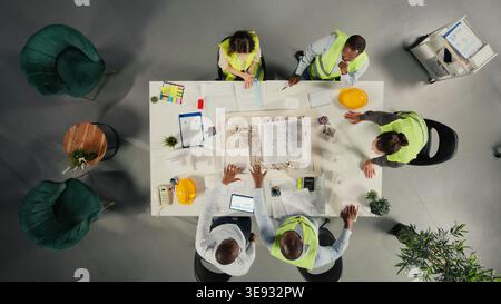Top down view of architects working on real estate investment plan. Business team analyzes property data, housing blueprints and trends to optimize land acquisition and projects. Stock Photo