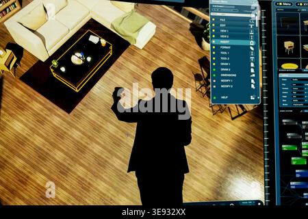 Interior decorator plans home renovation project using 3D modeling software. Designer uses VR controller to move furniture, trying out decoration styles on interactive digital interface Stock Photo