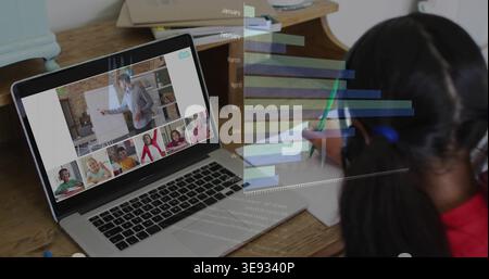 Writing schoolgirl in red top learning at home desk with laptop, chart, green pen, copy space Stock Photo