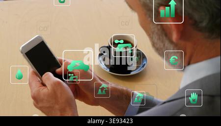Using smartphone, senior professional in suit viewing green AR icons at cafe table with black cup Stock Photo