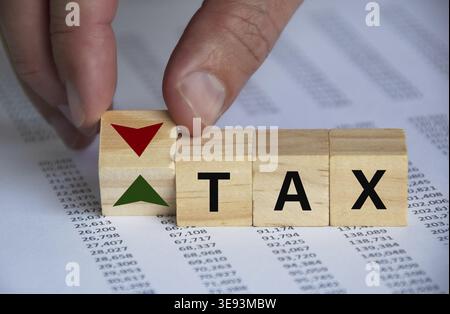 Tax word on wooden blocks with hand turn wooden block with up and down symbol. Taxation concept Stock Photo