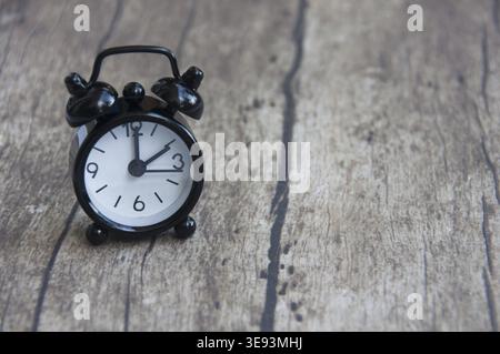 Black alarm clock isolated on wooden desk. The clock set at 2 o'clock. Deadline concept Stock Photo