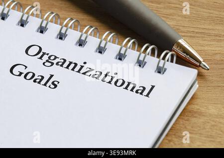 Close up notepad with the words Organizational Goals written on lined paper lying flat on a desk Stock Photo