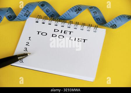 Diet to do list text on white notepad with blue measuring tape on yellow background. Health and diet concept Stock Photo