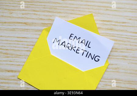 Email marketing text written on yellow notepad with envelope illustration clipped on wooden desk Stock Photo