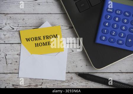 Top view of text - Work from home on notepad in an envelope with office setting background. Work from home concept Stock Photo