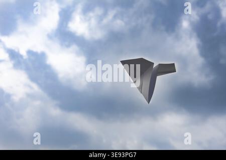 Flying white paper plane on blue sky background Stock Photo