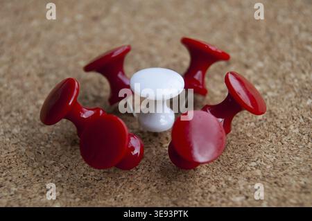 White push pin surrounded by red push pins. Harassment and discrimination concept Stock Photo