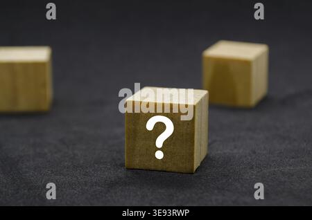Three wooden cubes with question marks aligned in a row Stock Photo