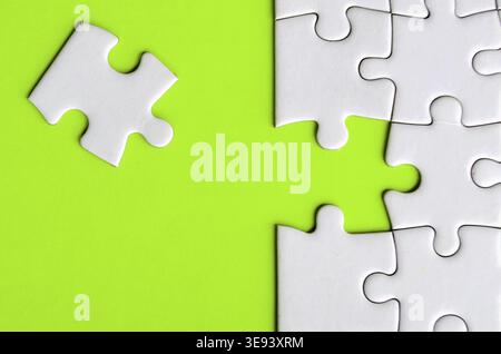 Connecting missing white jigsaw puzzle symbolizes partnership and unity on green background Stock Photo