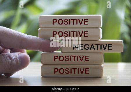 Hand pushing out negative out from positive - text on wooden blocks. Conceptual Stock Photo
