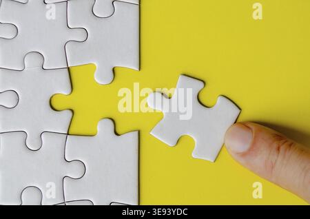 Hand fitting a missing white jigsaw pieces Stock Photo