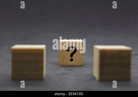Two dark wooden cubes with question marks on a black background Stock Photo