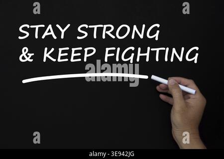 Stay strong and keep fighting text written on blackboard using chalk. Motivational concept Stock Photo