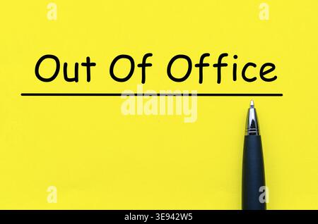 Out Of Office, Yellow square paper with black pen below the underlined phrase symbolizing absence notification note Stock Photo
