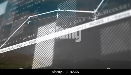 Displaying office screen showing source code and line chart at desk, hatched panels and faint hills Stock Photo