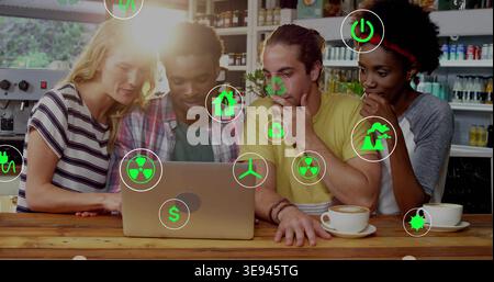 Collaborating group leaning over laptop at counter in cafe with green icons and two cups Stock Photo