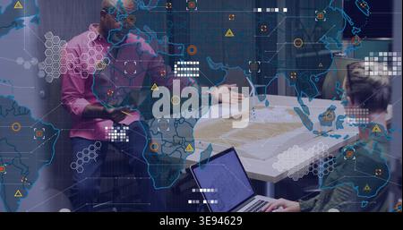 Discussing coworkers in pink shirt examining model and plans in office with laptop and map overlay Stock Photo