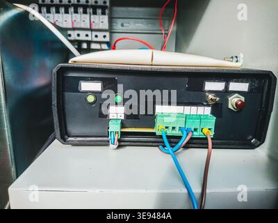 Detailed view of a black electronic device with green indicator lights, terminal blocks, and connected wires, part of a city's mobile communication in Stock Photo