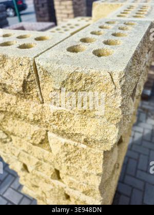 Detailed texture of rough yellow building blocks with circular perforations, showcasing their rough surface and construction material Stock Photo