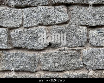 Rough gray stone wall with uneven blocks and visible mortar joints Stock Photo