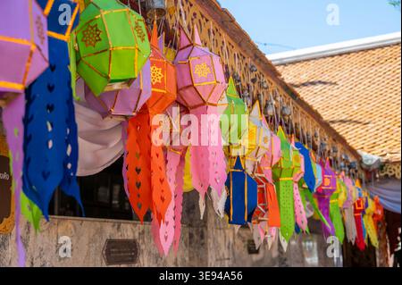Colorful Thai religious flags hanging from roof, decorative elements in temple, vibrant cultural scene with traditional ornaments, symbol of spiritual Stock Photo