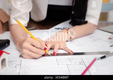 Female Architect working with pencil and ruler on blueprint. Architect engineer contractor design working drawing sketch plan blueprint and making arc Stock Photo