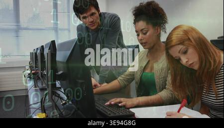 Typing trio collaborating on coding and notes in computer lab, with red pen, monitors and cables Stock Photo
