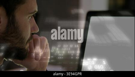 Leaning bearded man studying bright laptop at desk in dark sweater with binary overlay, copy space Stock Photo