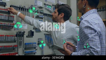 Reaching two techs inspecting shop pegboard in button-up shirts using tablet stylus with AR icons Stock Photo
