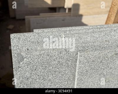 Granite slabs with speckled pattern stacked in sunlight, ideal for construction background. Mobile photo Stock Photo