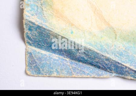 Detailed macro view of worn, textured paper showing intricate fibers and faded colors, suggesting age and history Stock Photo