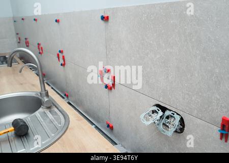 Installation of porcelain tiles for a kitchen backsplash using a tile leveling system. Home renovation. Ceramic tiles fixed with a leveling system Stock Photo