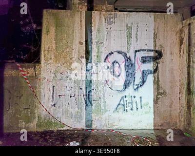 Concrete wall shows graffiti with lettering and red and white tape Stock Photo
