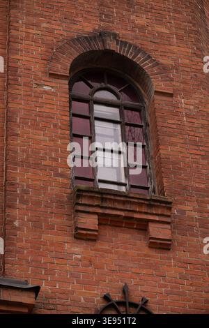 A moody architectural close up of an old brick facade featuring a classic arched window Stock Photo
