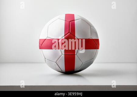 A soccer ball featuring England’s red cross on a white background, placed centrally with soft lighting and a minimal studio setup. Stock Photo