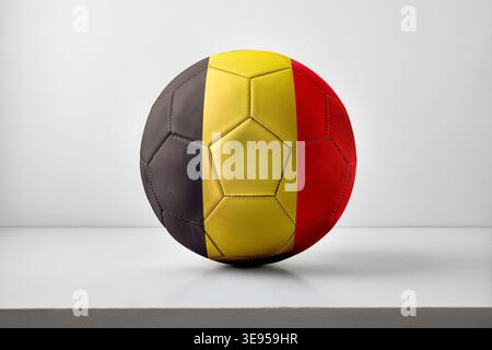 A soccer ball featuring Belgium’s black, yellow, and red vertical stripes, centered on a neutral background with soft lighting. Stock Photo