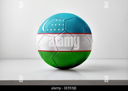 A soccer ball decorated with Uzbekistan's flag, including crescent and stars, displayed on a white surface with soft, even lighting. Stock Photo