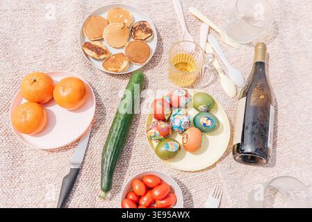 Picnic in nature Easter celebration with painted colored traditional eggs, fruits, vegetables and wine Stock Photo