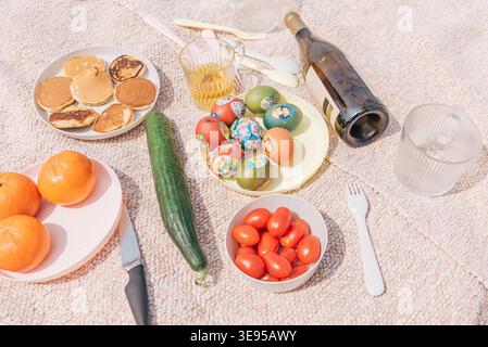 Picnic in nature Easter celebration with painted colored traditional eggs, fruits, vegetables and wine Stock Photo