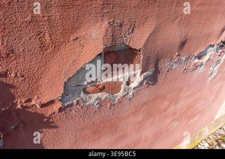 Old plaster on a house wall is weathered and chipped Stock Photo