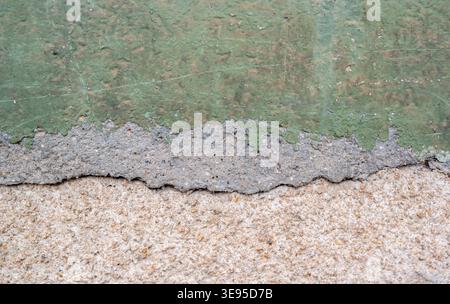Old green plaster on a house wall is weathered and chipped Stock Photo